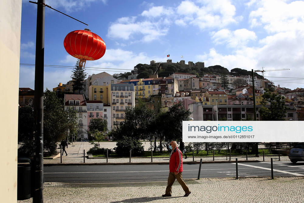 A men wearing a face mask walks under a red lantern that were put up for the Chinese New Year marking the Year of the Ox at Martin Moniz square in Lisbon, Portugal on February 12, 2021. This year, with restrictions imposed by the state of emergency in Portugal due to the COVID-19 pandemic, online broadcasting replaces Chinese New Year celebrations, such as the traditional parade with dragons, snakes and acrobats, which attracts hundreds of people every year to the Almirante Reis avenue, however the traditional red lanterns adorn the avenue, to mark the event. Lisbon Portugal - ZUMAf123 20210212_zap_f123_004