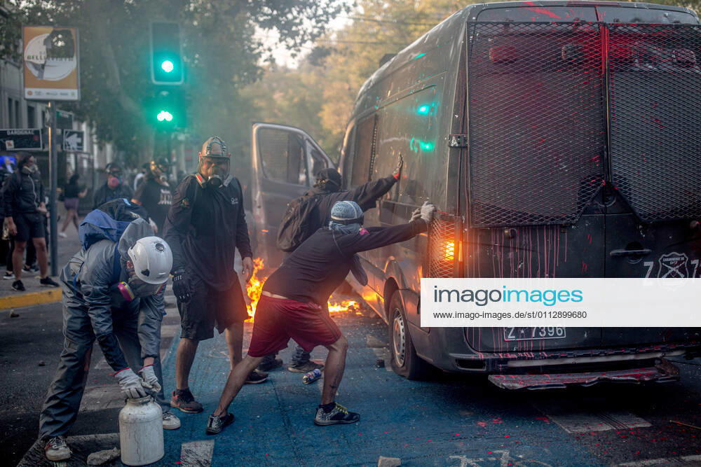 Protesters push and try to overturn a burning police vehicle during protests against police brutality in Santiago..Several protesters took to the streets in a protest against President Sebastian Pinera s government, attacking and burning a police vehicle hence injuring an officer following the death of a street artist who was shot by police in the city of Panguipulli after he refused to co-operate with a police search. Santiago Chile - ZUMAs197 20210212_zaa_s197_268