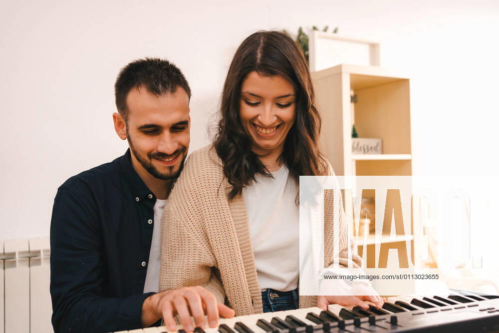 IMAGO Creative: Bildung, Musikerziehung Male musician playing synthesizer and singing together with woman while recording song at home