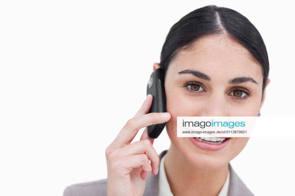 Close up of smiling businesswoman talking on cellphone Close up of smiling businesswoman talking on cellphone against a white background, model released, Cape Town, South Africa, 08.11.2011, 105737.jpg, beautiful, businesswoman, career, confident, elegant, employee, happy, pretty, smile, standing, full suit, worker, smiling, well dressed, brown hair, tied hair, brunette, mobile, phone, talking, calling, listening 20s, Young Adult, Woman, Female, Caucasian, 25-29 Years, Young Women, Caucasian Appearance Close-up,Copy space,Front view,Head and shoulders,Looking at camera,Studio shot,White background