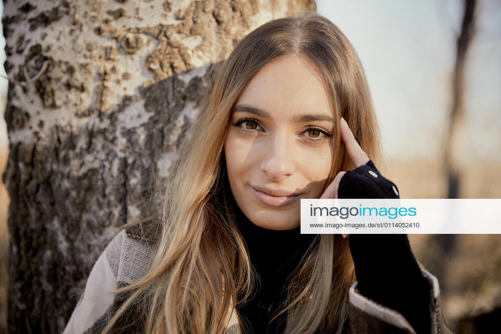 Beautiful blond woman against tree trunk at park on sunny day model released Symbolfoto ACPF01131