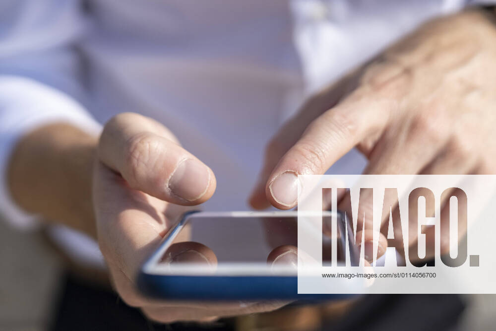 Businessman using smart phone outdoors during sunny day model released Symbolfoto BOYF01802