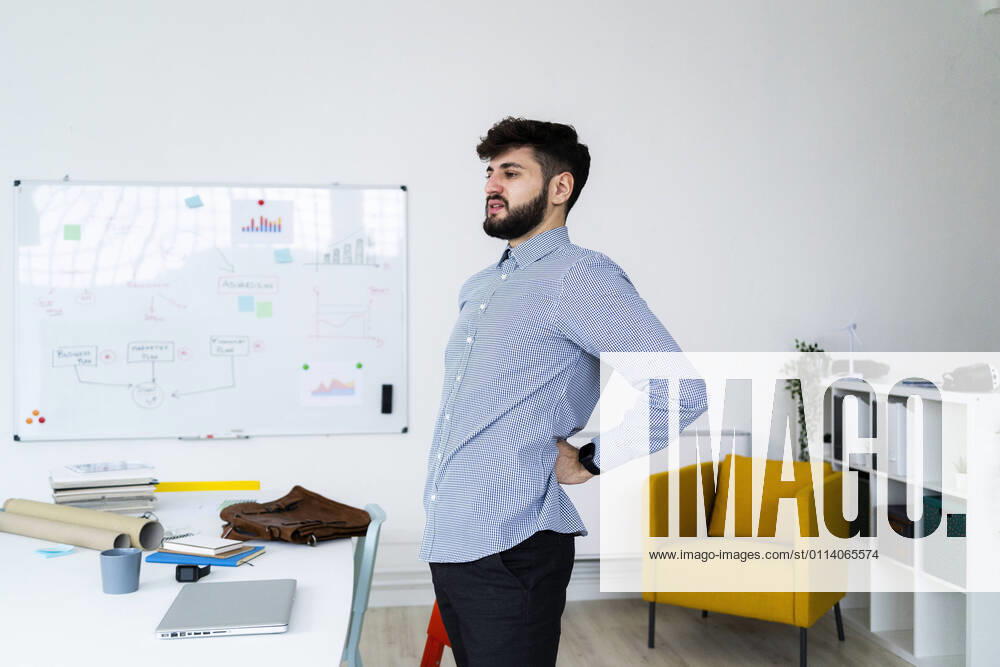 Tired businessman stretching in office model released Symbolfoto property released GIOF10574