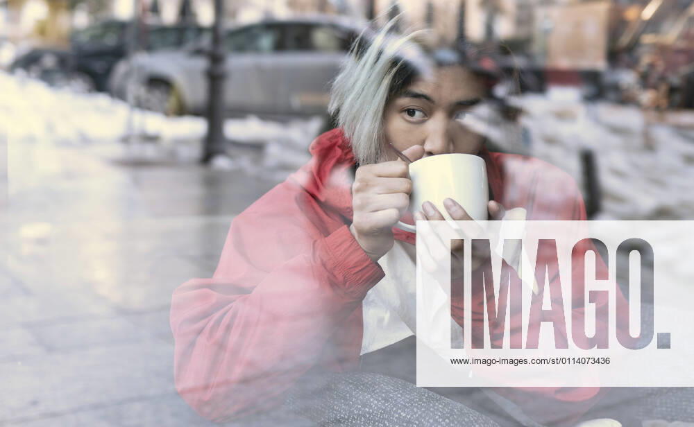 Asian man drinking coffee seen through glass in cafe during winter model released Symbolfoto JCCMF01139