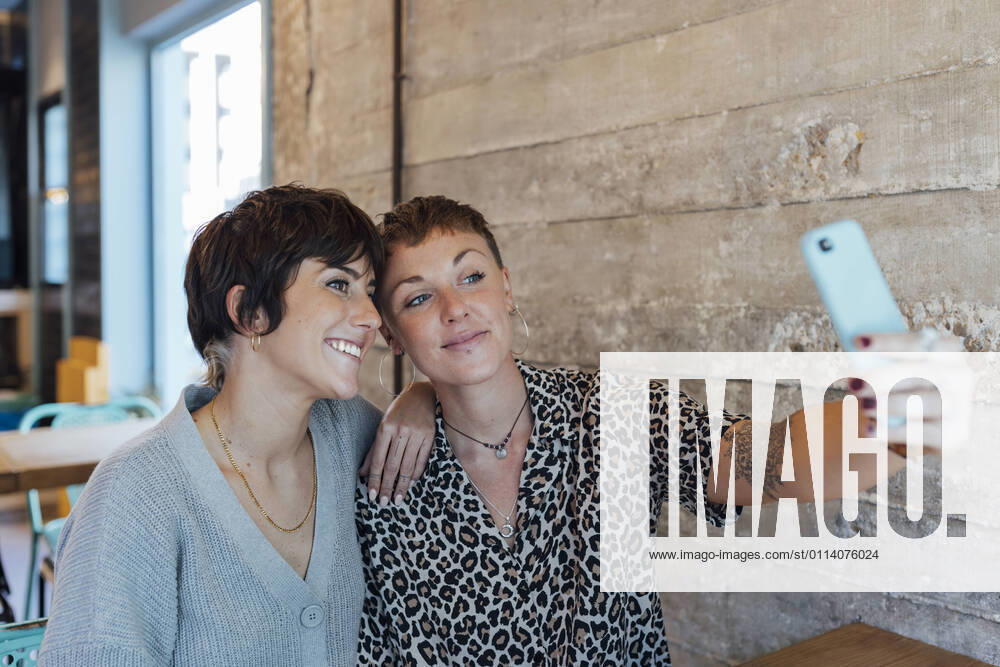 IMAGO Creative: Landleben - Essen Friends taking selfie on mobile phone while sitting at restaurant model released Symbolfoto property released JRVF00105