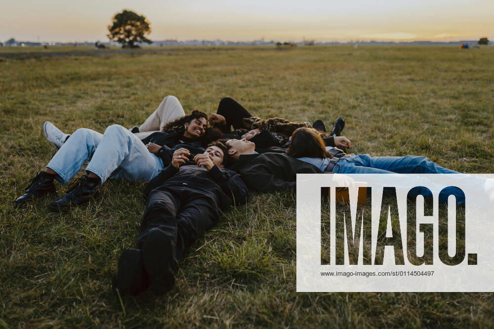 Young male and female friends lying on grass in park Germany, Berlin, model released