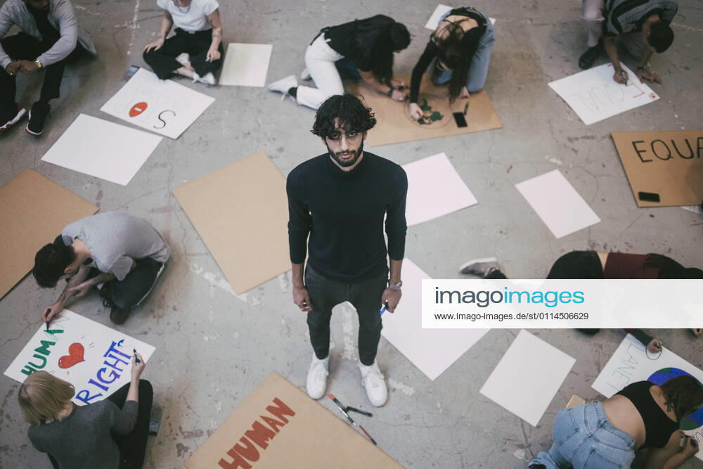 Portrait of man standing while male and female preparing signboards in building Sweden, Stockholm, model released, property released