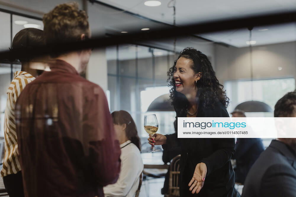 Cheerful female and male colleagues talking in company during party Sweden, Stockholm, model released, property released