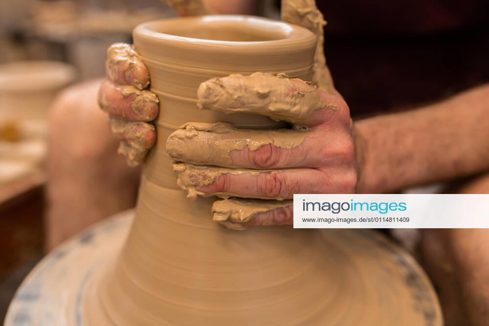 Crop unrecognizable sculptor with equipment giving shape while sculpting with brown clay on throwing wheel, Model released