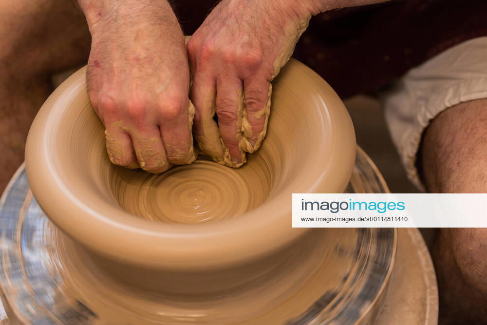 Crop unrecognizable sculptor with equipment giving shape while sculpting with brown clay on throwing wheel, Model released