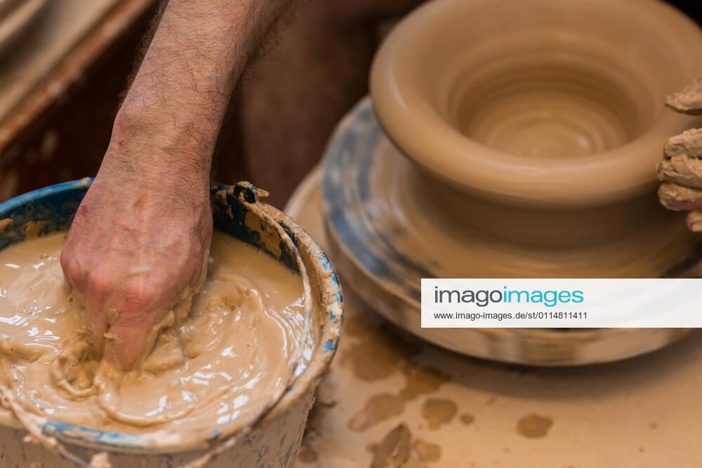 Crop unrecognizable sculptor with equipment giving shape while sculpting with brown clay on throwing wheel, Model released