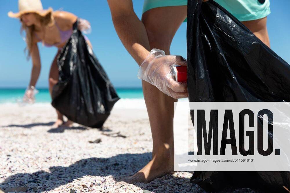 IMAGO Creative: Klimawandel - Umwelterziehung Young couple picking up the rubbish Mid section of a Caucasian couple on the beach with blue sky and sea in the background, picking up the rubbish to trash bags, model released, , property released, Cape Town, South Africa, 21.11.2019, 1310028.jpg, people,couple,together,interacting,bonding,romantic,real people,enjoy,enjoying,pleasure,lifestyle,free time,holidays,vacation,weekend,activity,relaxing,fun,health,healthy,outdoorsy,fit,leisure,beach,coast,coastal,sea,ocean,sand,sunny,summer,water,blue sky,eco-friendly,green,recycling,volunteer,volunteering,environment,cleaning,awareness,social responsibility,community,community spirit,helping,rubbish,collecting,trash,organised,teamwork,sun hat,millennial Young Adult,Woman,Female,Caucasian,Man,Ma