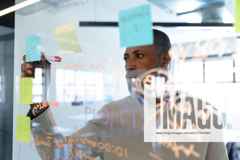 African American man writing on sticky notes Front view close up of a mixed race man working in a modern office, writing on a paper stick on a glass board. Social distancing and self isolation in quarantine lockdown, model released, , property released, Cape Town, South Africa, 12.10.2019, 1330111.jpg, social distancing, alone, quarantine, self isolation, real people, isolation, distance, lock down, people, creative, business, design professional, profession, professional, job, career, occupation, work, working, agency, company, creativity, casual, design, designer, start up, new business, entrepreneur, studio, office, workplace, modern, brainstorm, brainstorming, writing, glass wall, thinking, inspiration, information, logistics, strategy