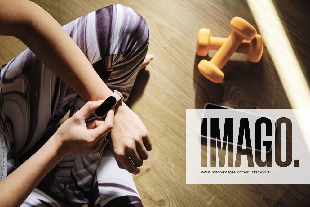 Young woman using smart watch while sitting cross-legged on floor at home model released Symbolfoto property released AODF00330