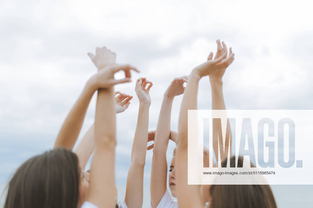 IMAGO Creative: Frühlingsferien und reisen Female friends raising arms together against sky model released Symbolfoto ARTF00028