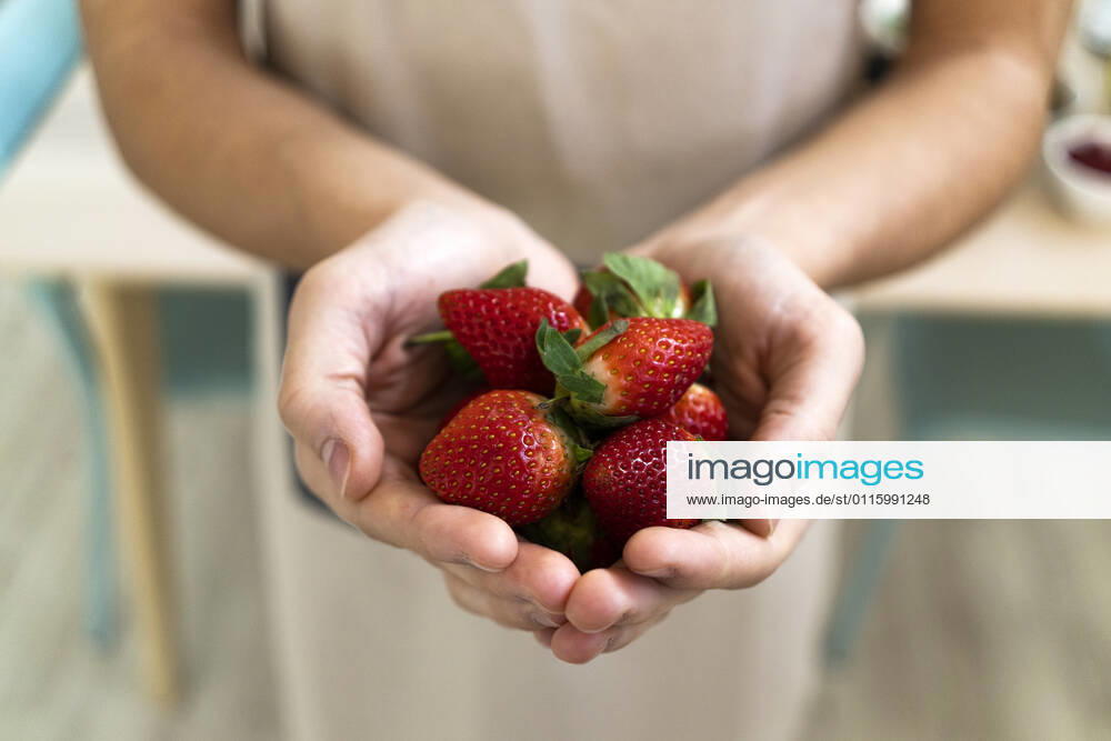 Man holding fresh strawberries in kitchen model released Symbolfoto property released GIOF11747
