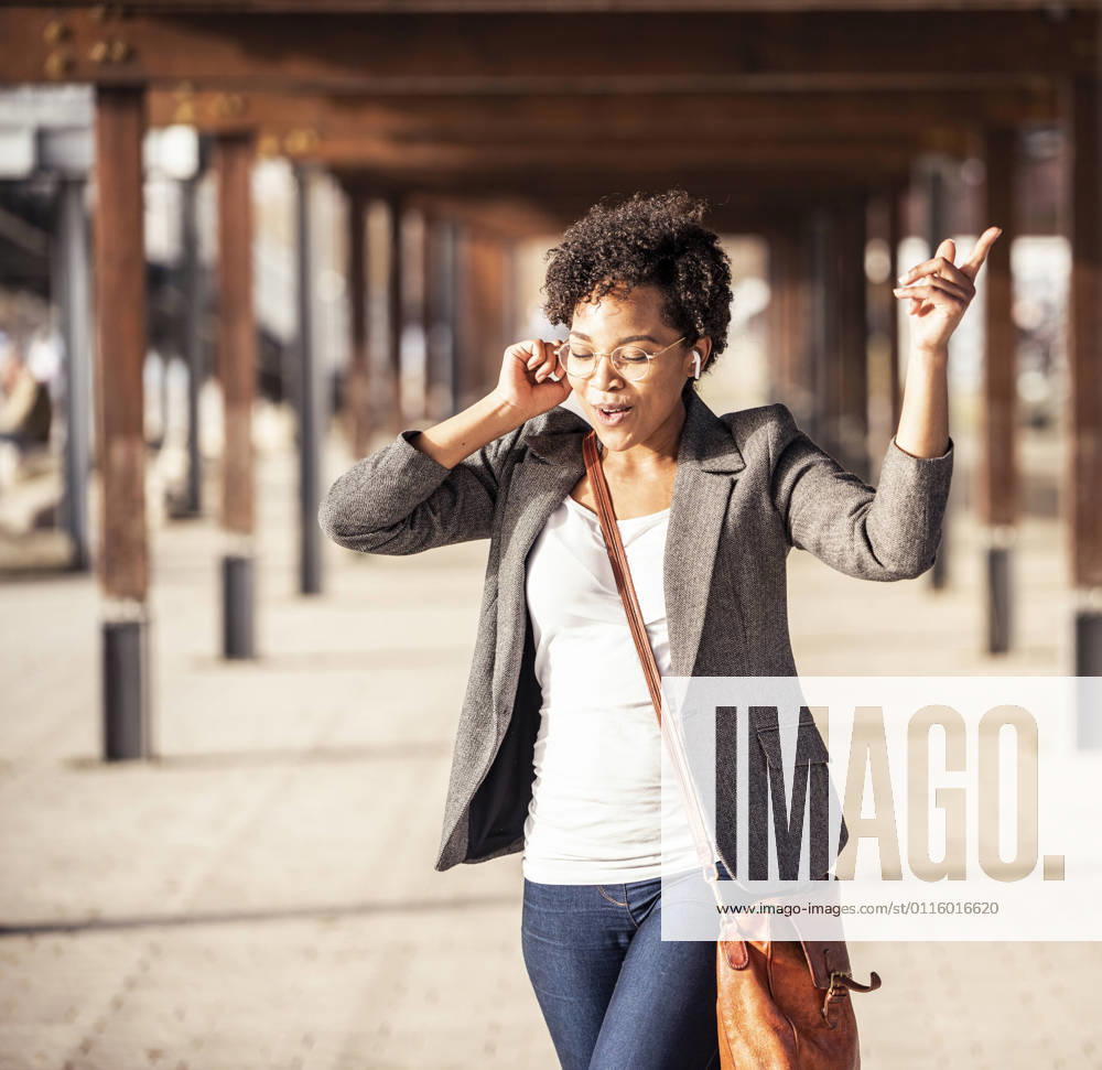 Young woman dancing while listening music on footpath model released Symbolfoto UUF23069