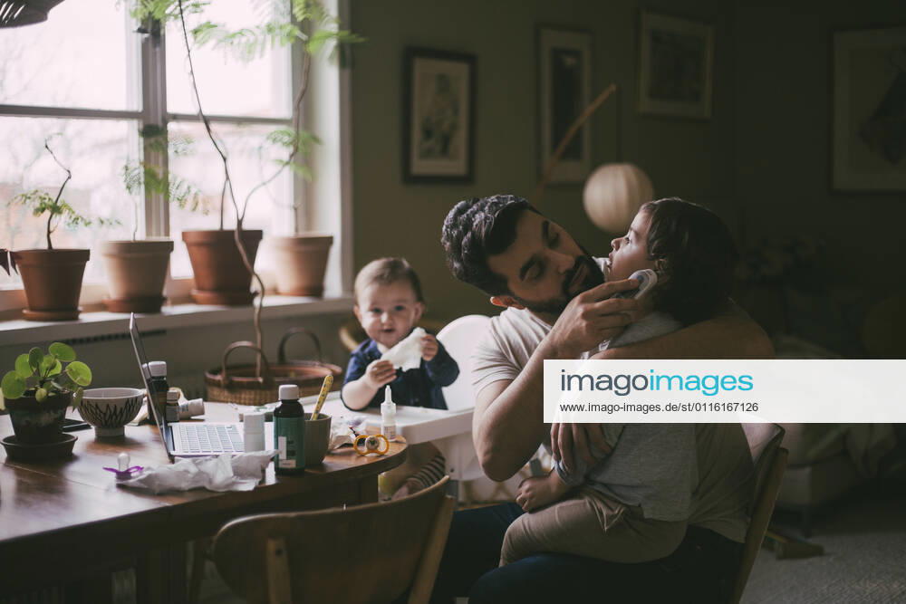 Father checking ear of son with otoscope at home Sweden, Stockholm, model released, property released