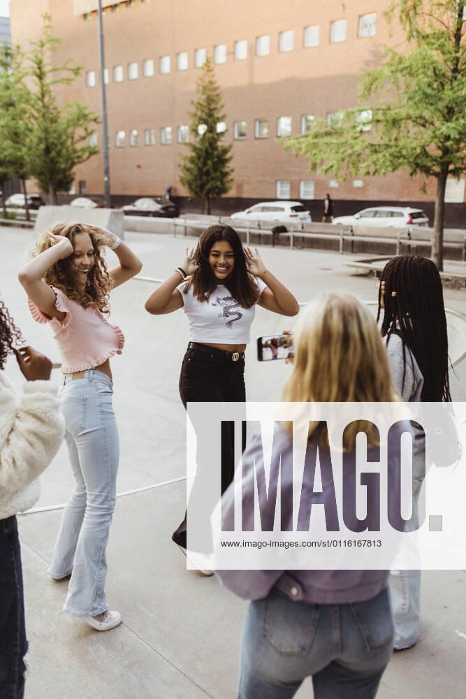 Teenage girls dancing while female friend recording video on smart phone at skateboard park Sweden,Stockholm, model released