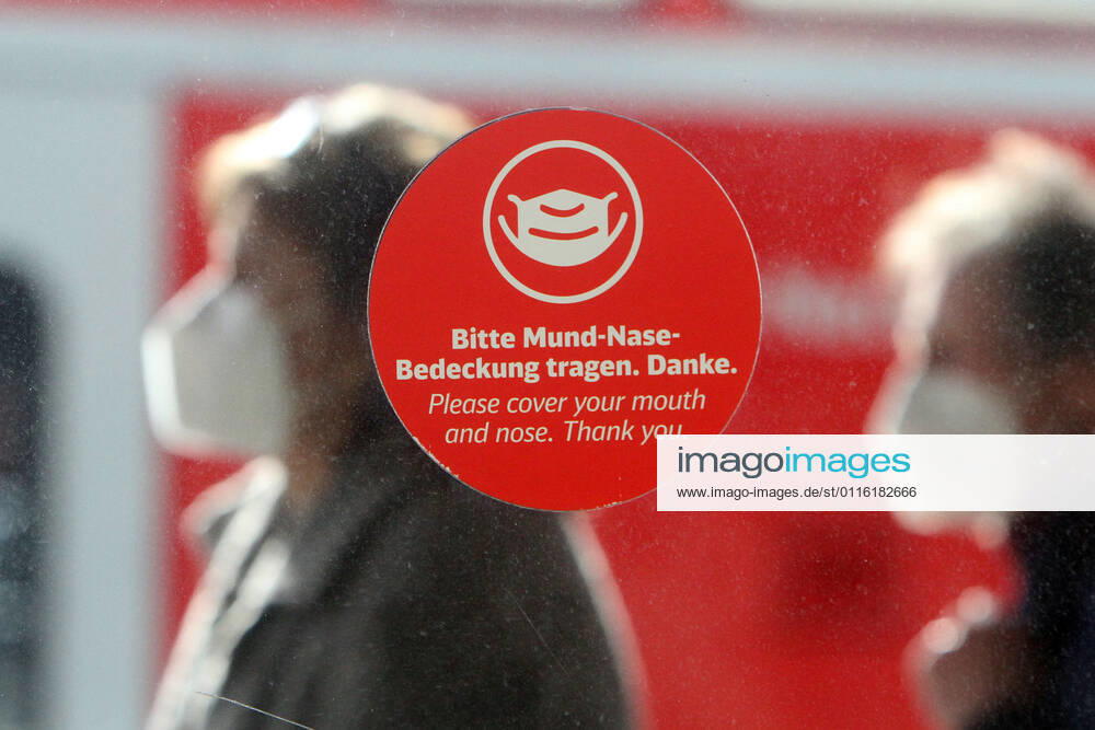 Sticker with pictogram and inscription please wear mouth-nose covering stuck on a window on the platform in the main station of Mannheim, Baden Württemberg, Germany