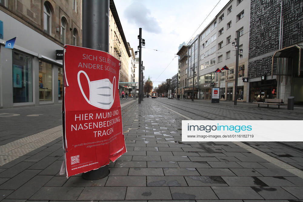 A sign with a pictogram and the inscription Maskenpflicht (mask obligation) hangs in the largely deserted pedestrian zone and shopping street Planken in the city centre of Mannheim, Baden Württemberg, Germany.