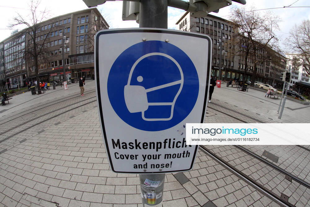 A sign with a pictogram and the inscription Maskenpflicht (mask obligation) hangs in the largely deserted pedestrian zone and shopping street Planken in the city centre of Mannheim, Baden Württemberg, Germany.