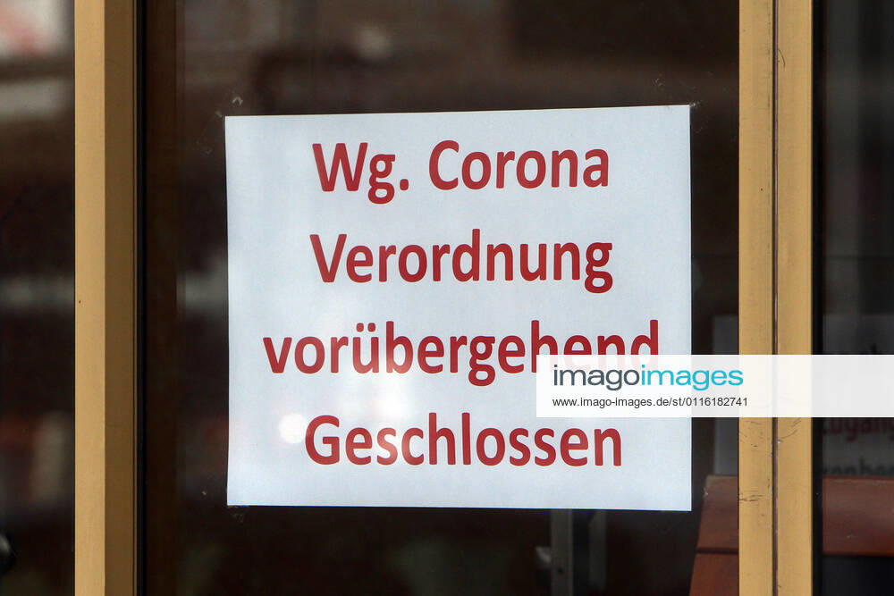 Sign with inscription temporarily closed due to Corona regulation hangs on the entrance door of a closed shop in downtown Mannheim, Baden Württemberg, Germany