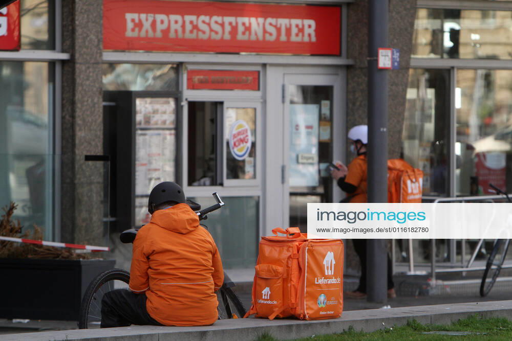 Bicycle courier from the internet portal Lieferando waits in front of a Burger King branch for food delivery in downtown Mannheim, Baden Württemberg, Germany