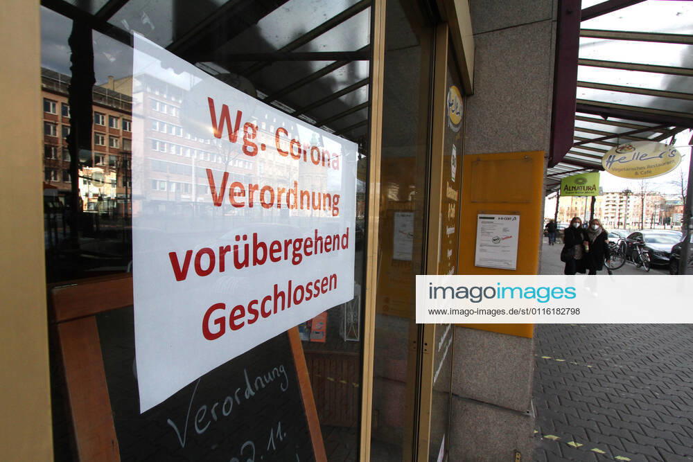 Sign with inscription temporarily closed due to Corona regulation hangs on the entrance door of a closed shop in downtown Mannheim, Baden Württemberg, Germany