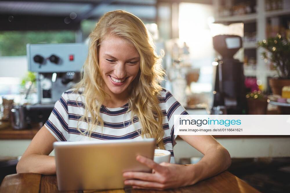 Woman sitting in a cafe using digital tablet Smiling woman sitting in a cafe using digital tablet, model released, , property released, Cape Town, South Africa, 30.05.2016, 797481.jpg, table, cafe, coffee shop, cafeteria, restaurant, hotel, casual clothing, sitting, holding, smiling, cheerful, web, internet, touching, reading, scrolling, digital tablet, tablet computer, tablet pc, touchscreen, wireless technology, communication, connection, happy, lifestyle, leisure, pretty, attractive Indoors,Day