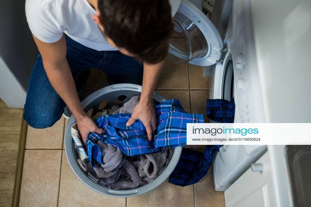 Man putting dirty clothes into washing machine Man putting dirty clothes into washing machine at home, model released, , property released, Cape Town, South Africa, 29.06.2016, 807974.jpg, home, house, household, homey, apartment, domicile, abode, kitchen, casual clothing, kneeling, looking, holding, washing machine, appliance, routine, housework, chore, bucket, clothes, washing, cleanliness, laundry, hygiene, leisure, lifestyle, domestic life Indoors,Day