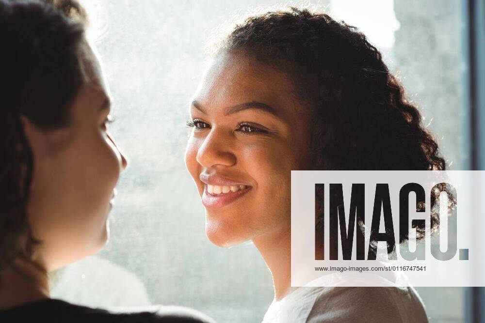 IMAGO Creative: Pride Month 2022, Engagement der Jugendlichen Lesbian couple smiling while having a conversation Close up of lesbian couple smiling while having a conversation, model released, , property released, Vancouver, Canada, 06.03.2017, 993028.jpg, home, house, household, homey, apartment, domicile, abode, authentic, real life, domestic life, smile, smiling, happy, window, bright, sunlight, talk, talking, conversation, interaction, sofa, happiness, light, glass, couple, relationship, adult, lesbian, lesbian couple, girlfriend, homosexual, partner, gay, youth, love, lover, affection, lifestyle, together, leisure, bonding, milleninial