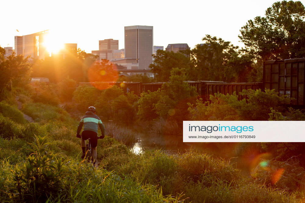 IMAGO Creative: Corporate: Klimaschutz, Digitalisierung und Urbanisierung IMAGO Creative: Klimawandel - Zukunft und Innovation Mountain biker at sunrise with Richmond skyline in the background. United States, Virginia, Richmond CR_KYLA210413-691106-01 ,model released, Symbolfoto