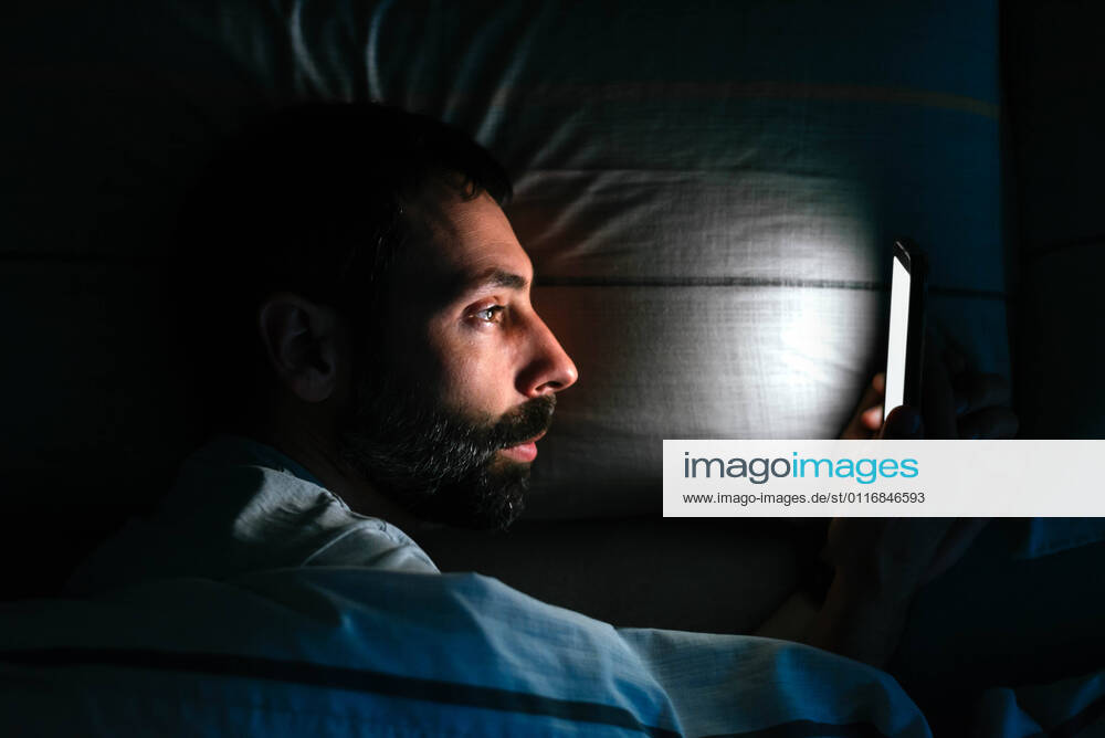 Young man using smartphone in bed Vigo, GA, Spain CR_AIMA210416-697310-01 ,model released, Symbolfoto