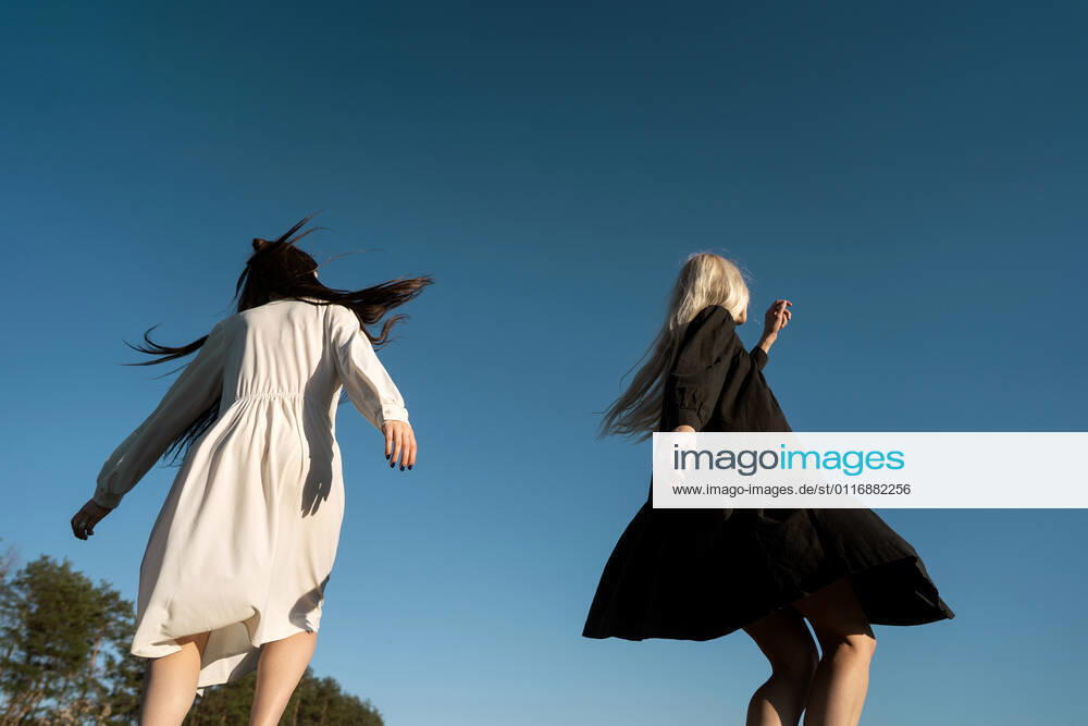 Two beautiful twin girls doing style lying in a field at sunset CR_NAOS210419-715200-01 ,model released, Symbolfoto
