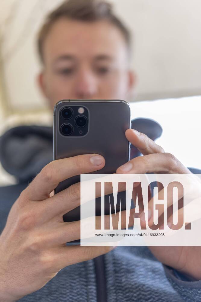 Young man taps on, holding iPhone 11 Pro, smartphone