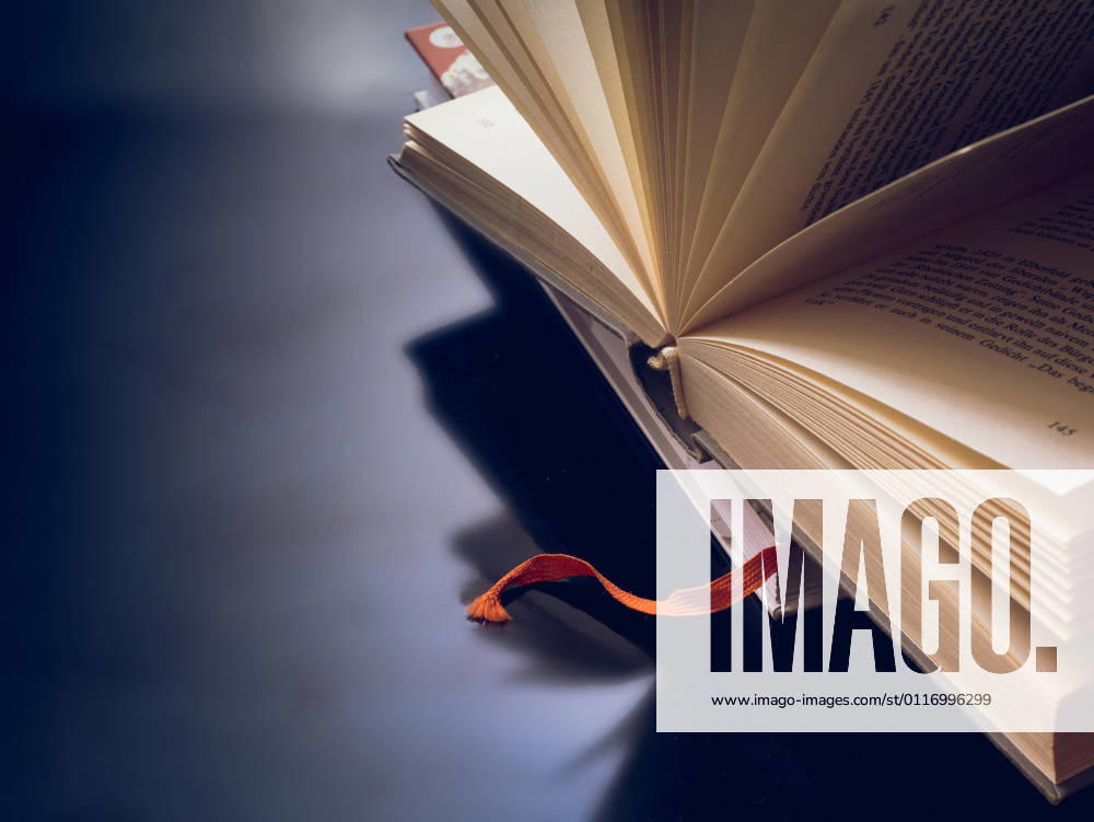 Opened and fanned book in front of dark background with text free space 1028901438