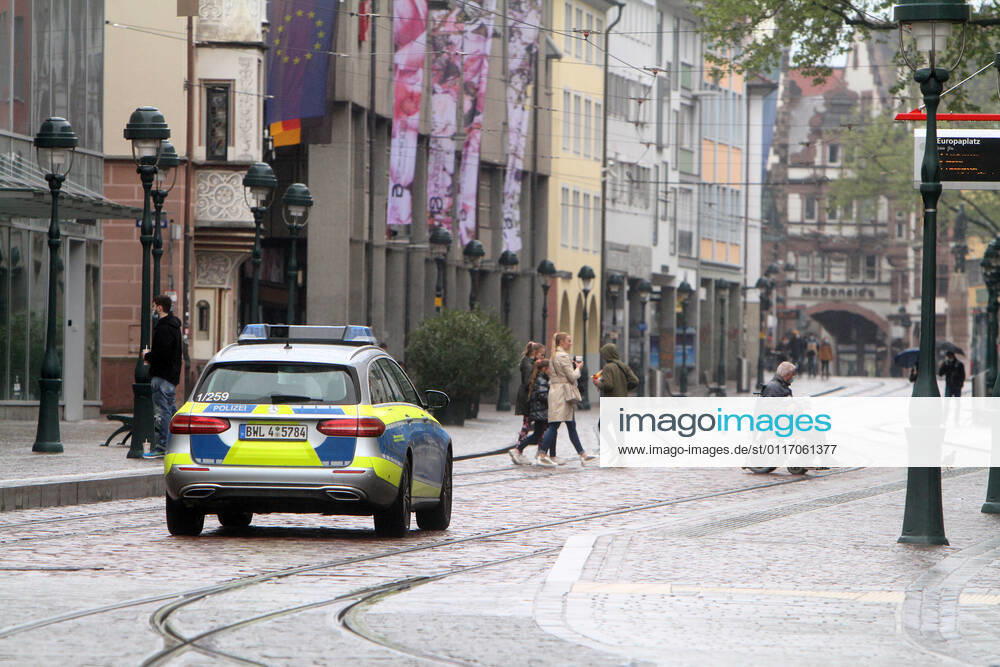 A police patrol of the state police of Baden Württemberg drives through the almost deserted pedestrian zone and shopping street Kaiser Joseph Straße in the city center of Freiburg, Baden Württemberg, Bavaria, Germany.