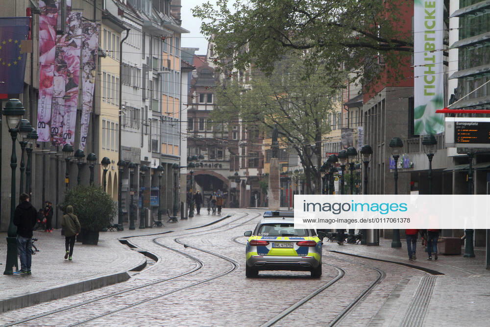 A police patrol of the state police of Baden Württemberg drives through the almost deserted pedestrian zone and shopping street Kaiser Joseph Straße in the city center of Freiburg, Baden Württemberg, Bavaria, Germany.