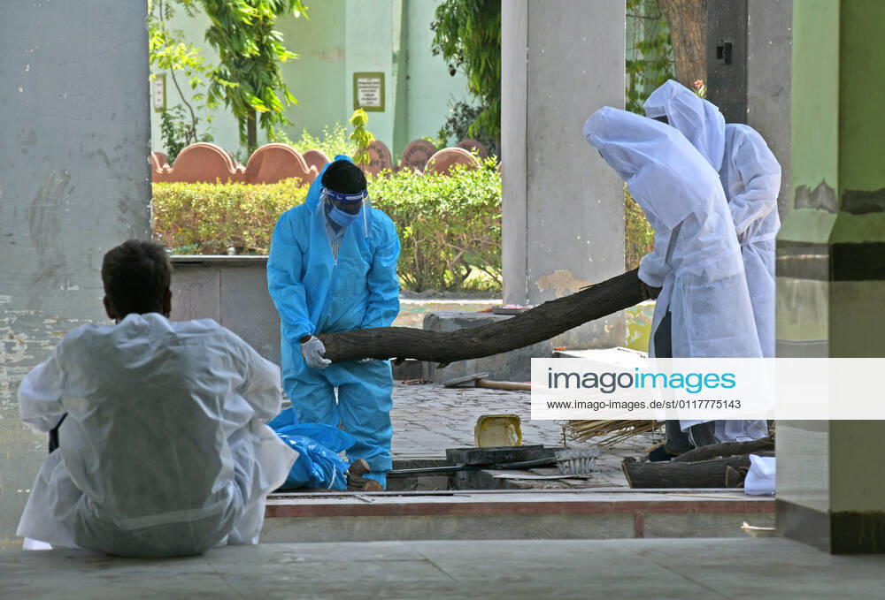Cremation Of COVID-19 Victims In Rajasthan, India Family members, wearing protective suits, prepare wooden pyre for cremation of COVID-19 victim at Hindu Moksha Dham crematorium in Beawar. Beawar Rajasthan India