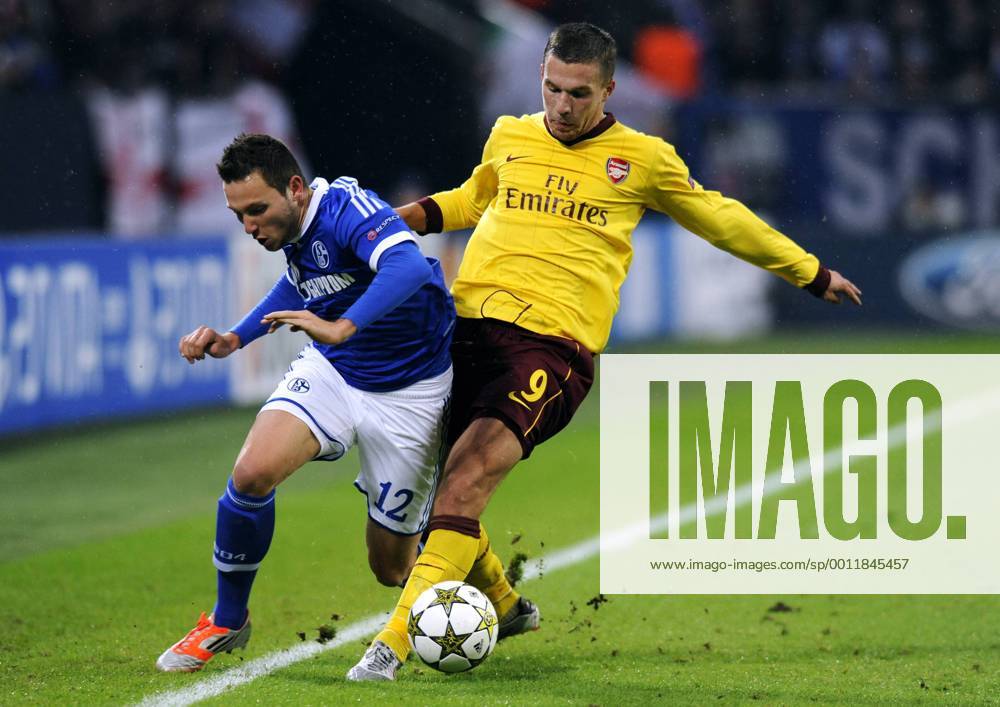 Fussball, UEFA Champions League, Herren, Saison 2012 2013, 4. Spieltag, Gruppe B, Veltins-Arena Gelsenkirchen, FC Schalke 04 (blau) - Arsenal London (gelb) 2:2; Marco Höger, Hoeger (S04), Lukas Podolski (Arsenal), Aktion.