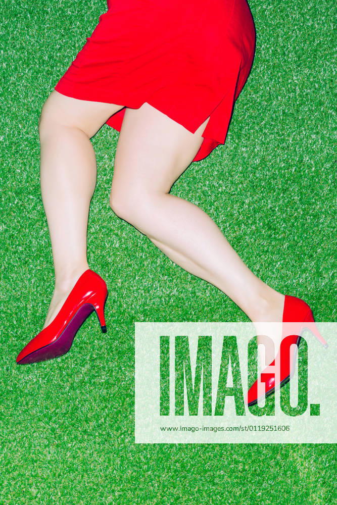 Top view of crop anonymous female in patent red shoes lying on grassy ground