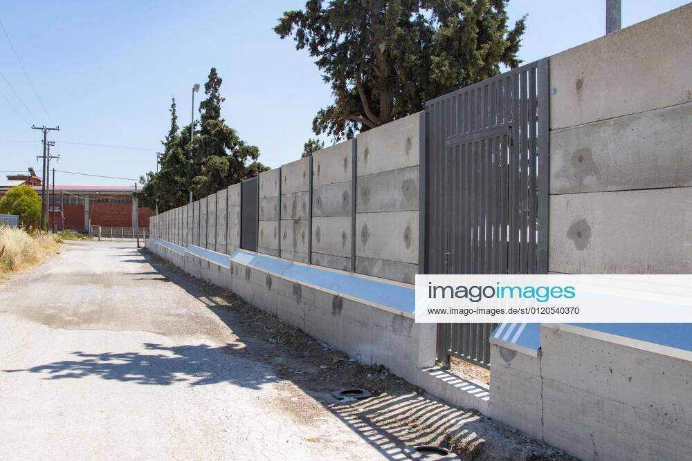 New Concrete Walls Around Diavata Refugee Camp In Greece Greece is building new concrete walls around the refugee camps across the country in the mainland and the islands. The 3meter wall was a decision by the Greek Ministry of Migration and European Commission. Asylum seekers feel like imprisonment conditions while the authorities claim its for their own security, monitoring the entrance and locking the camp during the night. Diavata refugee and migrant camp is a former military camp near the city of Thessaloniki in Northern Greece. The concrete fortification called enhanced fence has been built around the whole area of the camp. Diavata, Greece on June 6, 2021 Thessaloniki Greece economou-notitle210605_npoaZ
