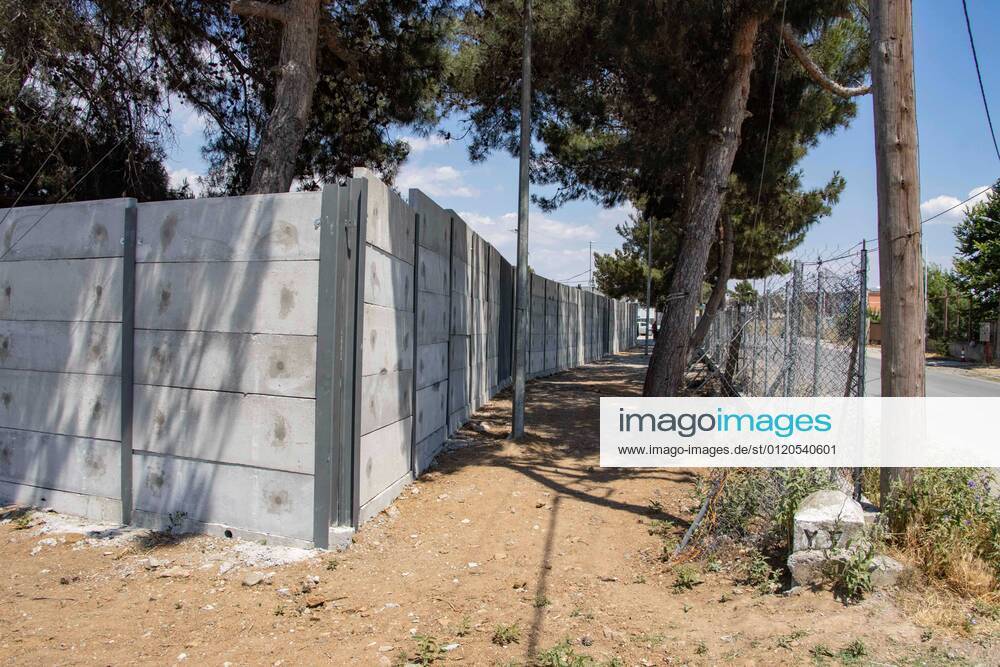 New Concrete Walls Around Diavata Refugee Camp In Greece Greece is building new concrete walls around the refugee camps across the country in the mainland and the islands. The 3meter wall was a decision by the Greek Ministry of Migration and European Commission. Asylum seekers feel like imprisonment conditions while the authorities claim its for their own security, monitoring the entrance and locking the camp during the night. Diavata refugee and migrant camp is a former military camp near the city of Thessaloniki in Northern Greece. The concrete fortification called enhanced fence has been built around the whole area of the camp. Diavata, Greece on June 6, 2021 Thessaloniki Greece economou-notitle210605_npe0C