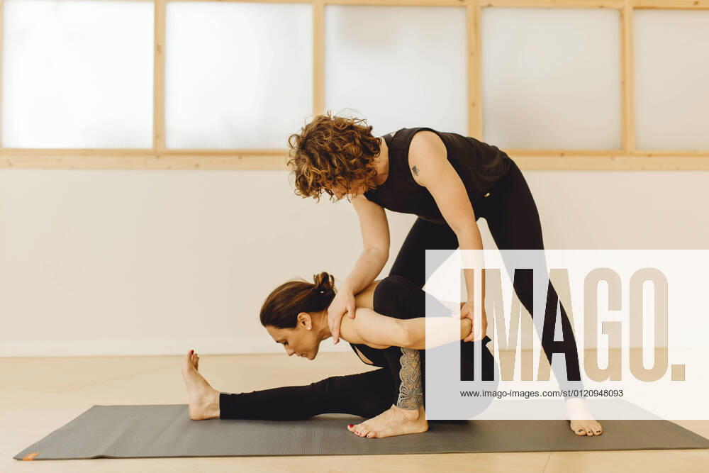 IMAGO Creative, Neujahr, Vorsätze, Sport Attractive yoga teacher woman helping young woman with pose in training room, Model released