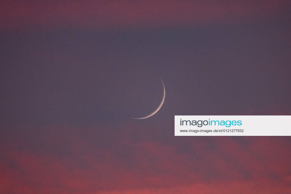 Two days old new moon in the sky over Aachen against a background of pink clouds that owe their color to the sunset. In Aachen on June 12, 2021 GERMANY - AACHEN - WEATHER