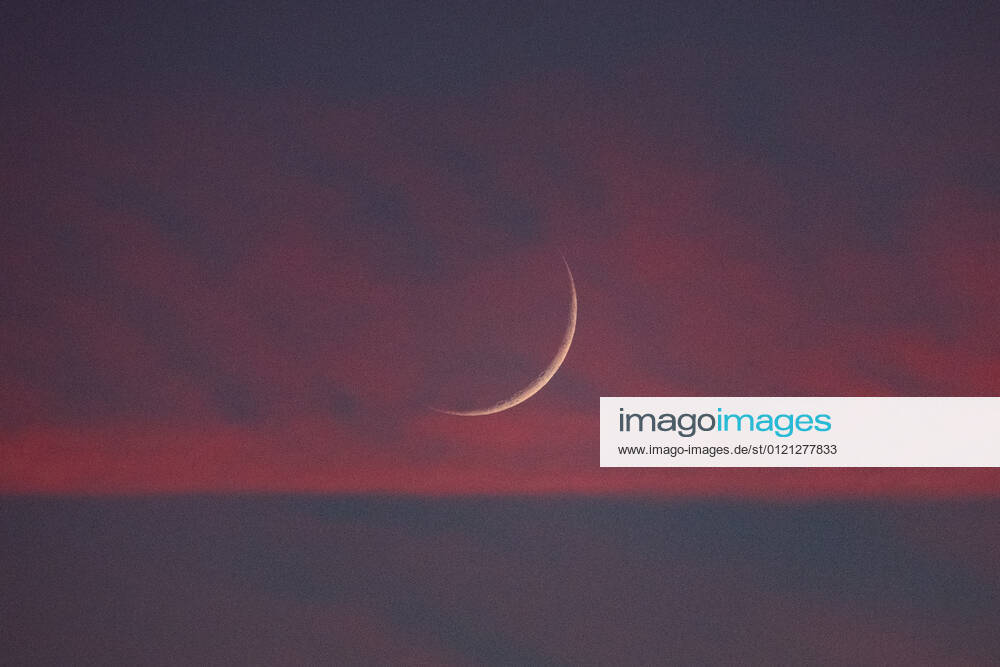 Two days old new moon in the sky over Aachen against a background of pink clouds that owe their color to the sunset. In Aachen on June 12, 2021 GERMANY - AACHEN - WEATHER