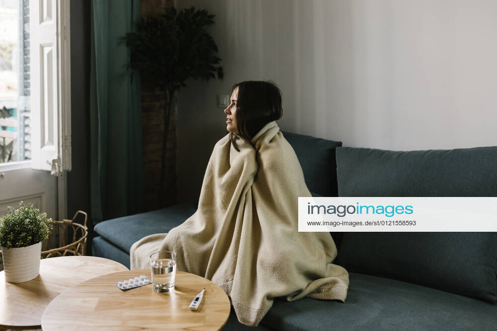 Sick woman looking away while wrapped in blanket at home model released Symbolfoto property released XLGF01620