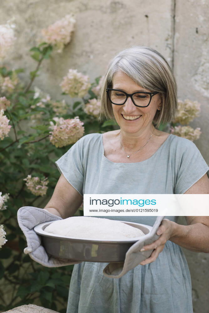 Excited woman carrying baked bread pan at back yard model released Symbolfoto property released ALBF01616