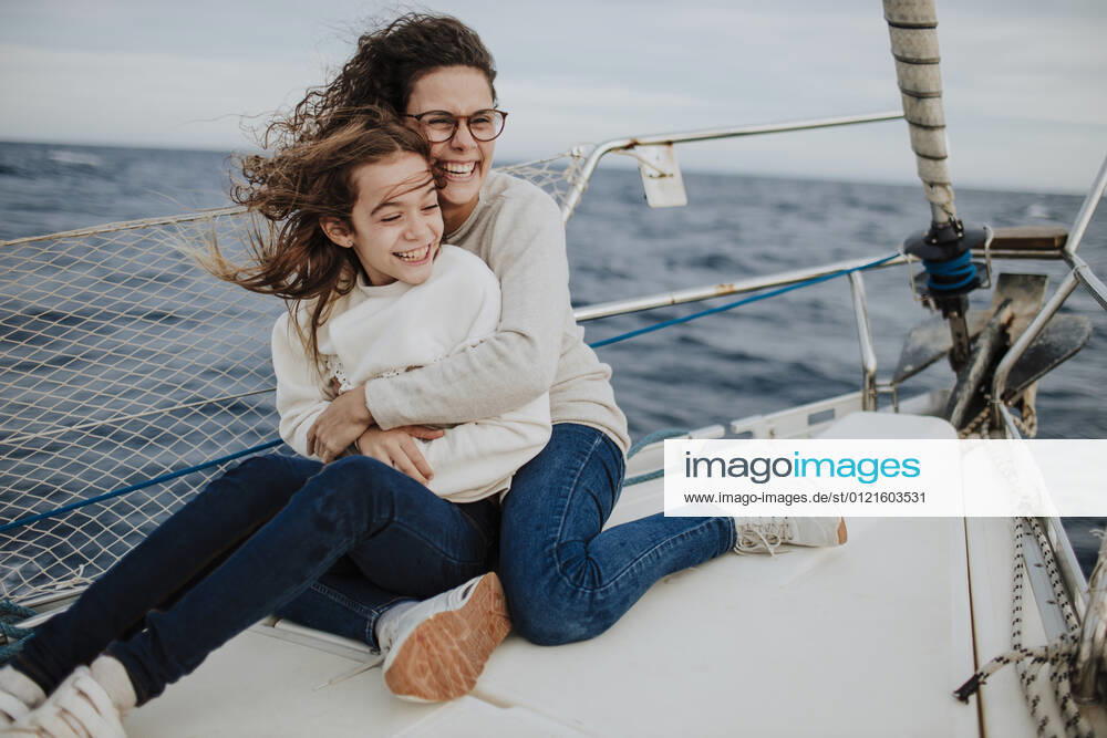 Cheerful mother embracing daughter while traveling on sailboat model released Symbolfoto GMLF01167